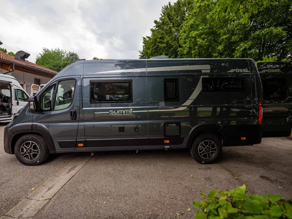 Summit Prime 640 – Graues Pössl Summit Prime 640 Reisemobil von der Seite, Hecktüren offen.