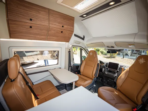 Columbus Liner – Gemütliche Sitzgruppe und Fahrerbereich mit Ledersitzen im Reisemobil.