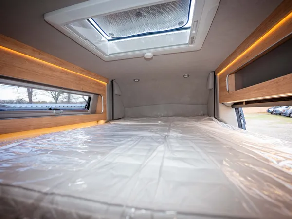 Avanti F – Bettbereich eines Reisemobils mit Fenster, Dachluke und Stauschrank, Matratze foliert.
