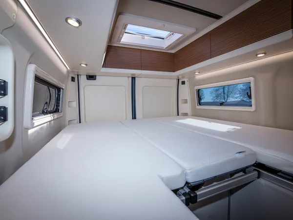 Columbus 600 E – Bettbereich im Reisemobil mit Matratzen, Fenstern und Dachluke.