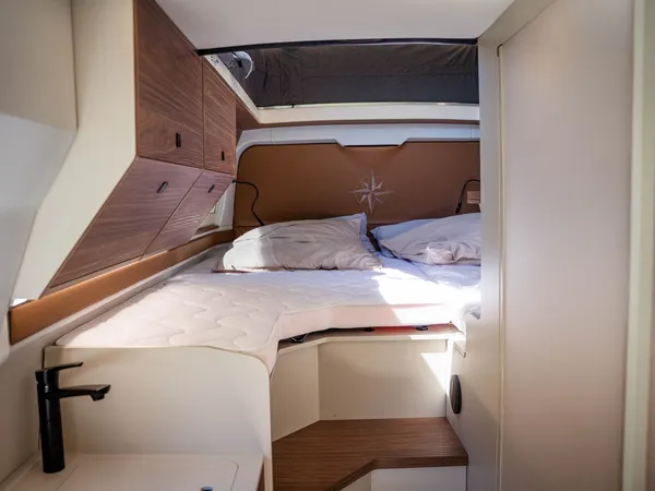 Columbus Liner – Blick ins bequeme Bett mit Kopfende und Oberschränken im Reisemobil.