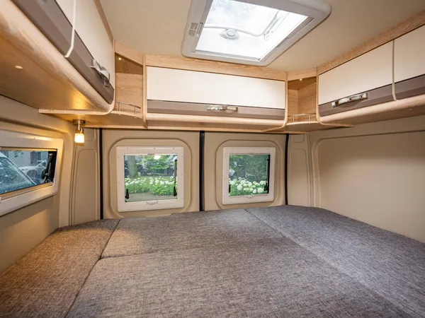 Summit 600 B – Bettbereich im Reisemobil mit Fenstern und Oberschränken