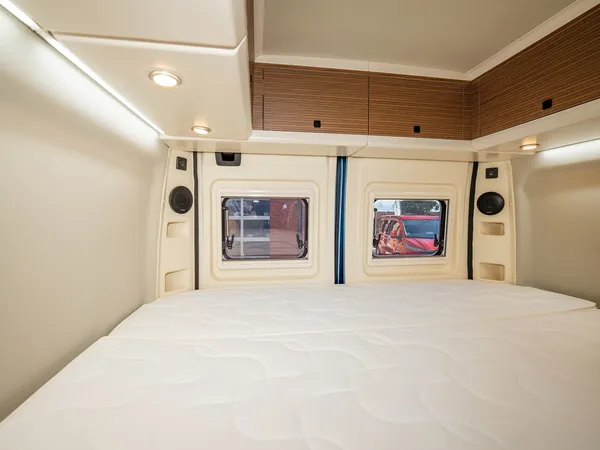 Columbus 540 D – Blick auf das Heckbett mit Fenstern und Oberschränken im Reisemobil.