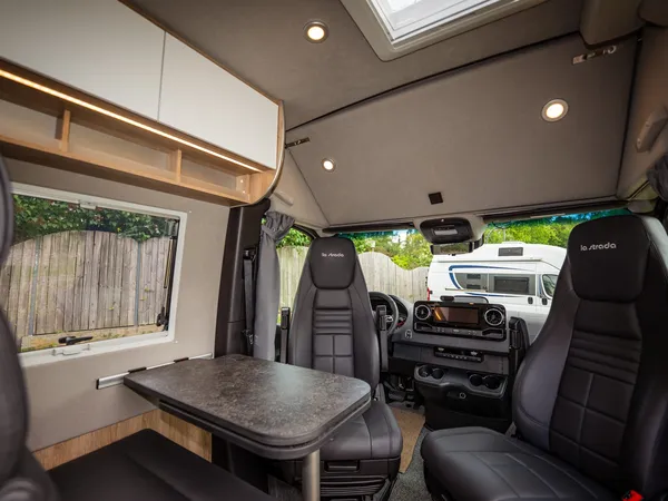 Regent EB – Sitzgruppe mit Tisch und drehbaren Vordersitzen im Reisemobil.