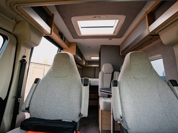 Trenta 640 – Blick vom Fahrerhaus in den Wohnraum des Campers mit Sitzgruppe und Bett.