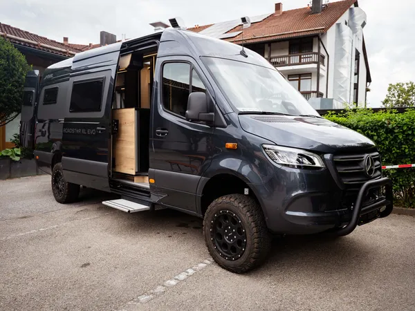 Roadstar XL Evo – Dunkelgraues Roadstar XL Evo Reisemobil schräg von vorne, Schiebetür offen.