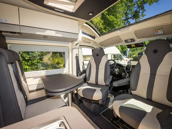 Nansen 640LS – Gemütliche Sitzgruppe im Reisemobil mit drehbaren Vordersitzen und Tisch.