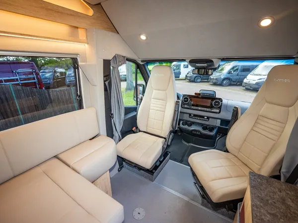 Nova M – Geräumiges Cockpit eines Nova M Reisemobils mit drehbaren Sitzen und Sitzgruppe.