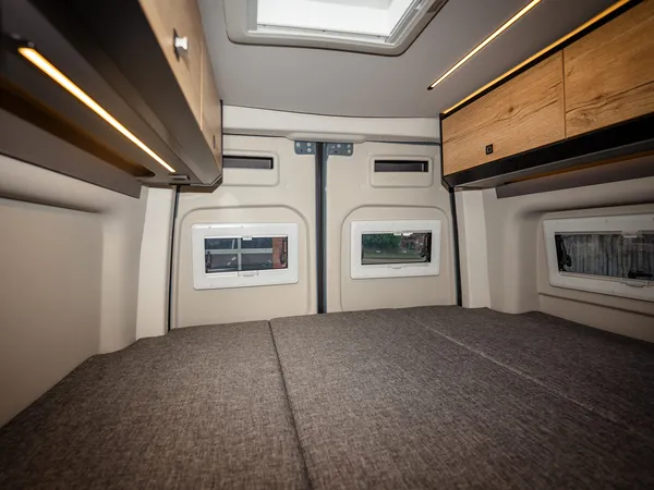 Roadstar XT – Bettbereich im Reisemobil mit Fenstern und Oberschränken