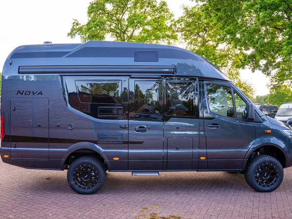 Nova M – Dunkelgraues Reisemobil Nova M von der Seite, geparkt unter Bäumen.