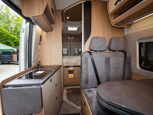 Roadcruiser Revolution – Blick durch das Wohnmobil auf Küche, Sitzgruppe und Bettbereich.