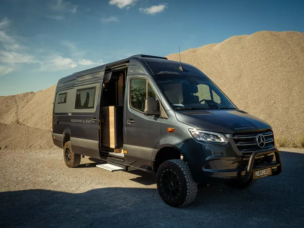 Roadstar XL Evo – Roadstar XL Evo Camper von vorne schräg mit offener Tür vor Kieshaufen.