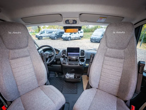 Avanti EB – Blick vom Wohnraum ins Fahrerhaus mit Armaturenbrett und Sitzen.