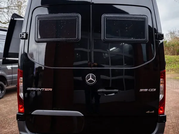 Roadstar X – Schwarzes Roadstar X Reisemobil, Heckansicht mit zwei Fenstern und Sprinter-Schriftzug.