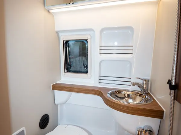 Columbus 600 D – Modernes Badezimmer mit Toilette, Waschbecken und Duschbrause im Reisemobil.