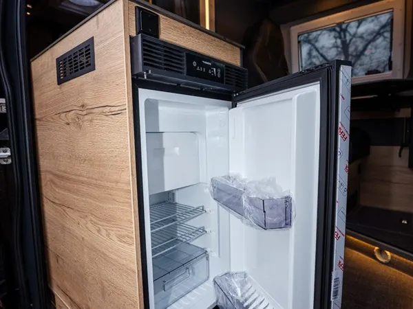 Roadstar X – Offener Kühlschrank in einem Reisemobil, integriert in Holzmöbel.