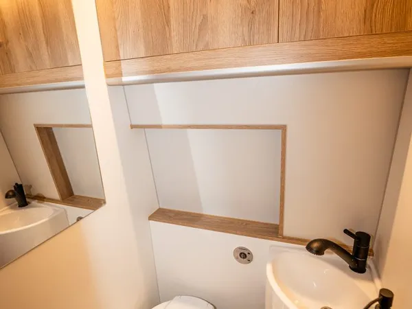 Avanti EBF – Modernes Bad mit Toilette, Waschbecken und Holzschränken im Reisemobil.