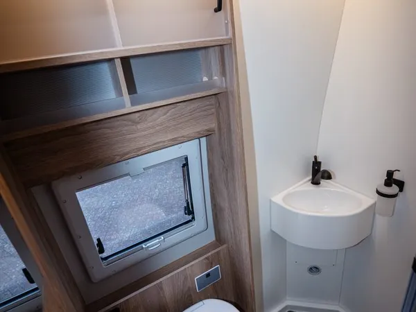 Avanti C – Modernes Badezimmer im Reisemobil mit Toilette, Waschbecken und Fenster.