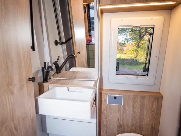 Regent E – Modernes Bad mit Waschbecken, Toilette, Spiegel und Fenster im Reisemobil.