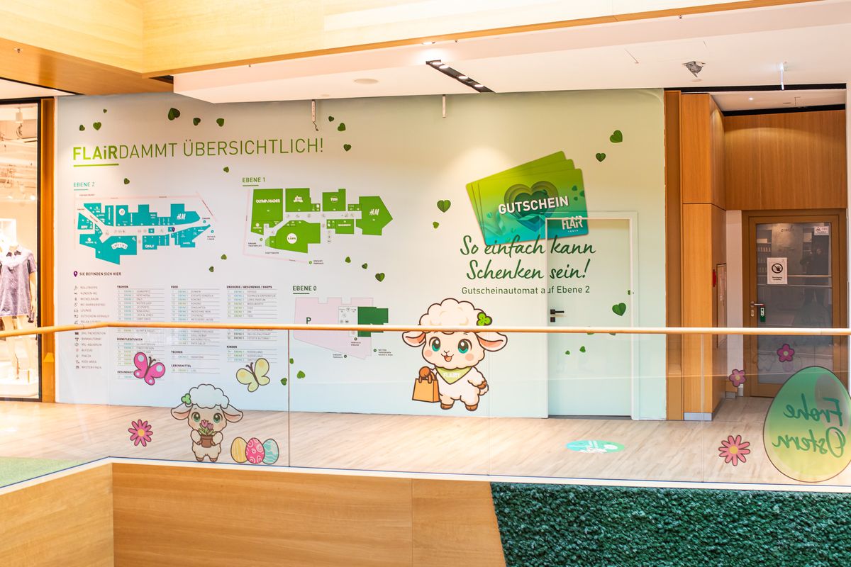 Wandgestaltung „FLAiRdammt übersichtlich!“ im FLAiR Fürth: Lagepläne der Ebenen 0 bis 2, Gutschein-Motiv, FLAiRY-Schafe und Oster-Deko an der Glasbrüstung