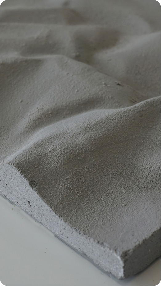 Nahaufnahme einer grauen Betonplatte mit wellenförmig strukturierter Oberfläche auf weißem Untergrund