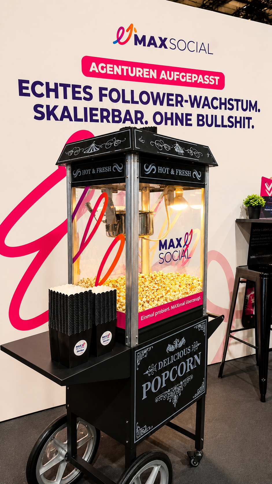 Gebrandete Popcornmaschine mit MAXSOCIAL Logo und Slogan „Einmal probiert. MAXimal überzeugt.“ vor der Messerückwand