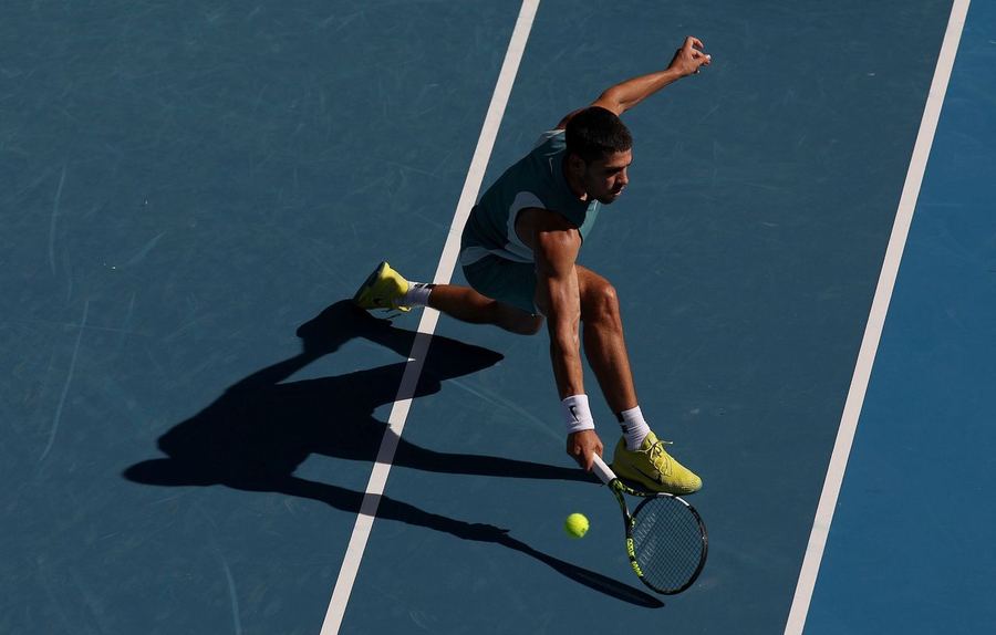 Tennisspieler streckt sich auf blauem Hardcourt nach dem Ball, Aufnahme von oben