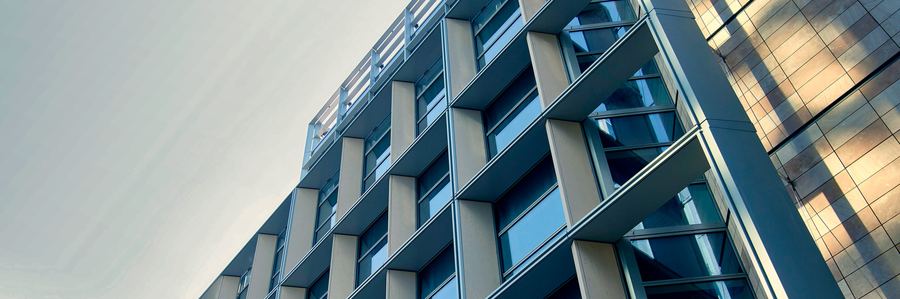 Untersicht einer modernen Bürofassade aus Glas, Sichtbeton und Metall