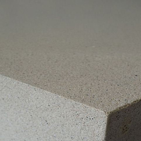 Nahaufnahme der Kante einer grauen Glasfaserbetonplatte mit feinkörniger, gesprenkelter Oberfläche
