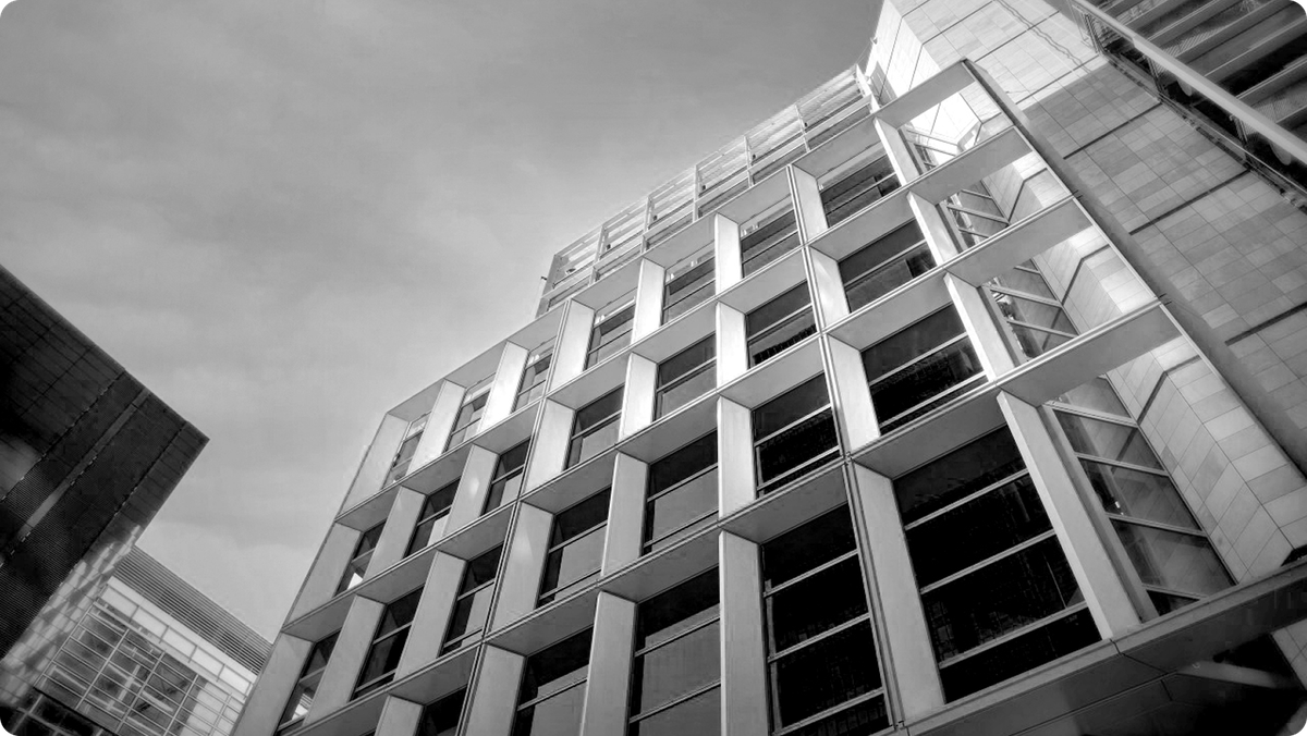 Schwarz-Weiß-Aufnahme einer modernen Bürofassade mit tiefen Rahmenelementen, von unten fotografiert