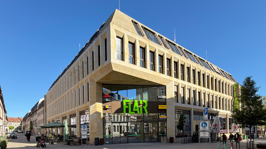 Außenansicht des FLAiR Fürth bei Tageslicht: Sandsteinfassade mit grünem FLAiR-Schriftzug über dem Eingang Hallstraße