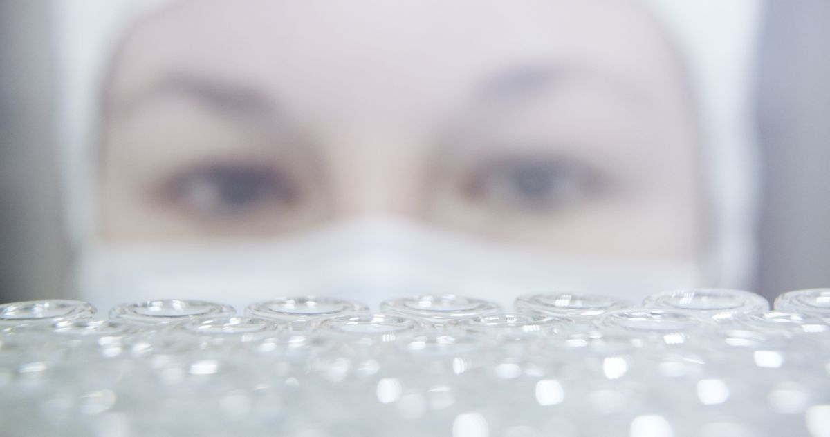Standbild aus dem Imagefilm: scharf gestellte Reihen leerer Glasfläschchen, dahinter unscharf das Gesicht einer Mitarbeiterin mit Mundschutz