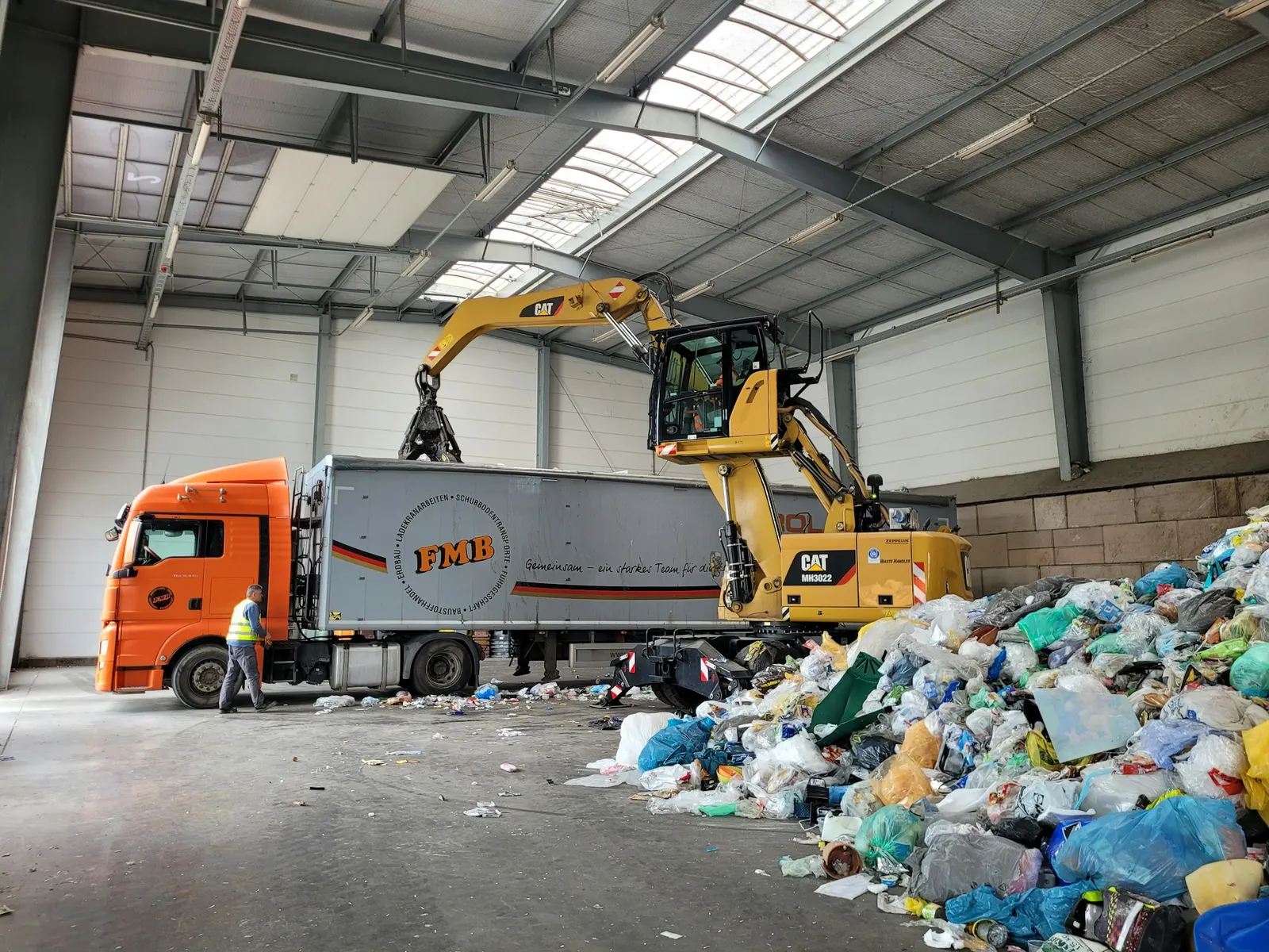 Material handler loading a truck at a waste transfer facility
