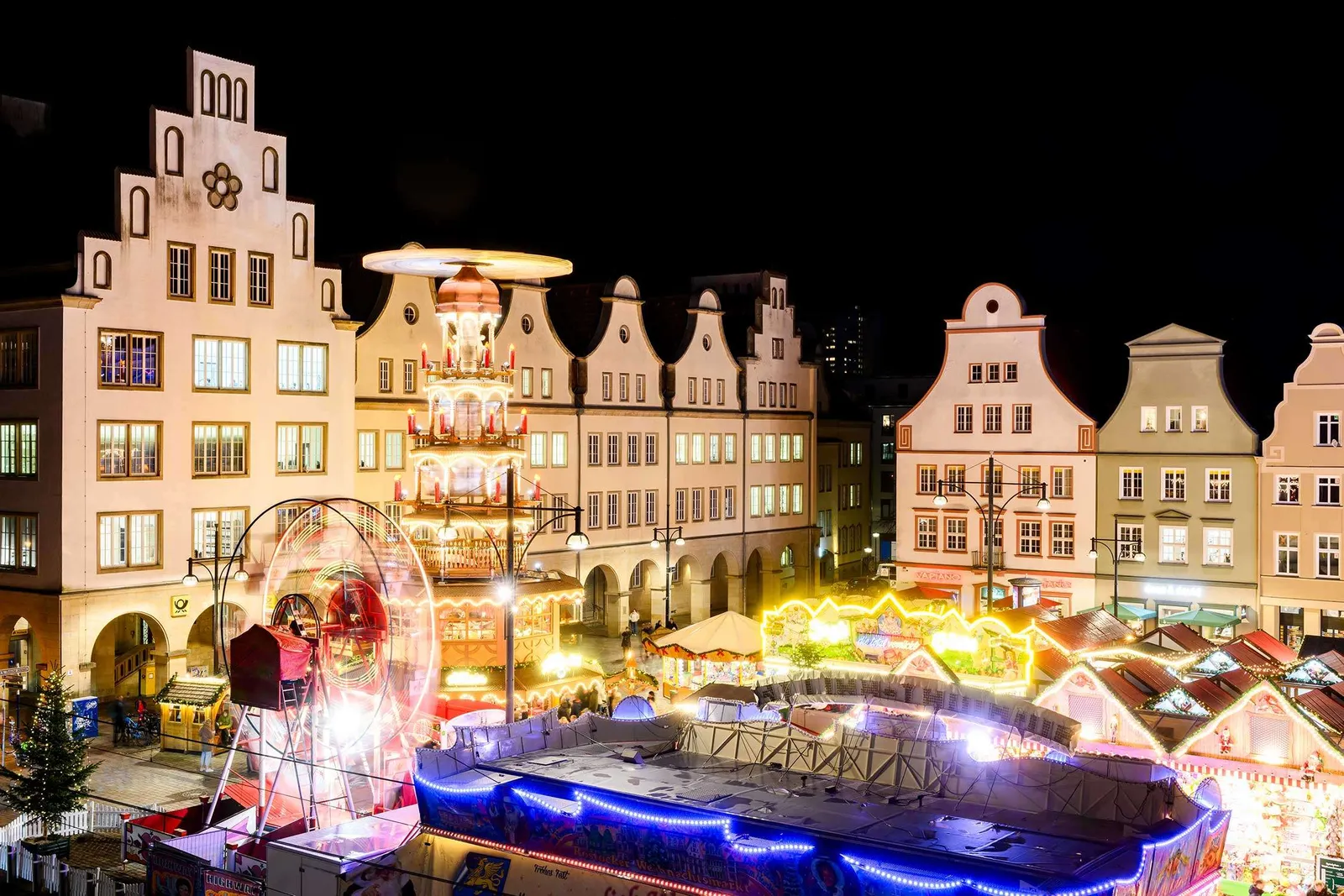 Rostocker Weihnachtsmarkt bei Nacht mit einem Riesenrad, festlich beleuchteten Häusern und Ständen