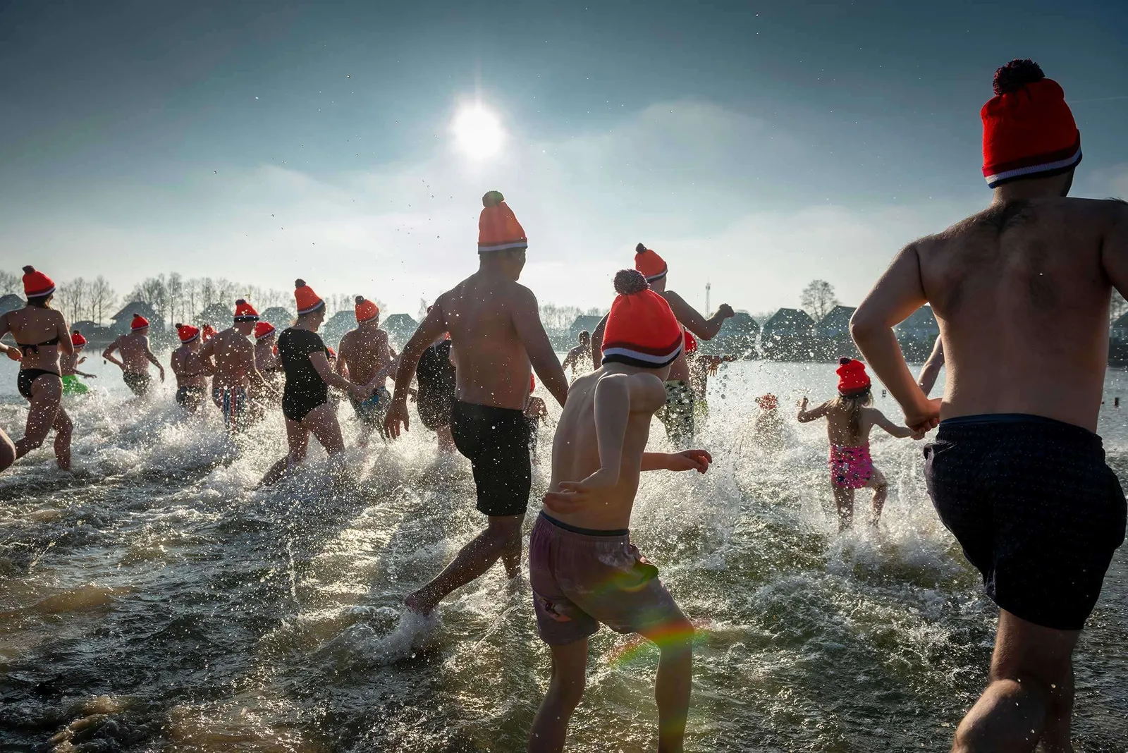 Gruppen von Menschen, darunter Kinder, springen in die kalten Wellen des Meeres während des traditionellen