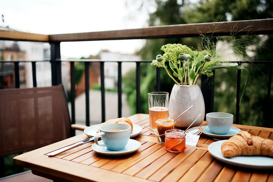 Gedeckter Frühstückstisch mit Kaffee und Croissants auf dem Balkon
