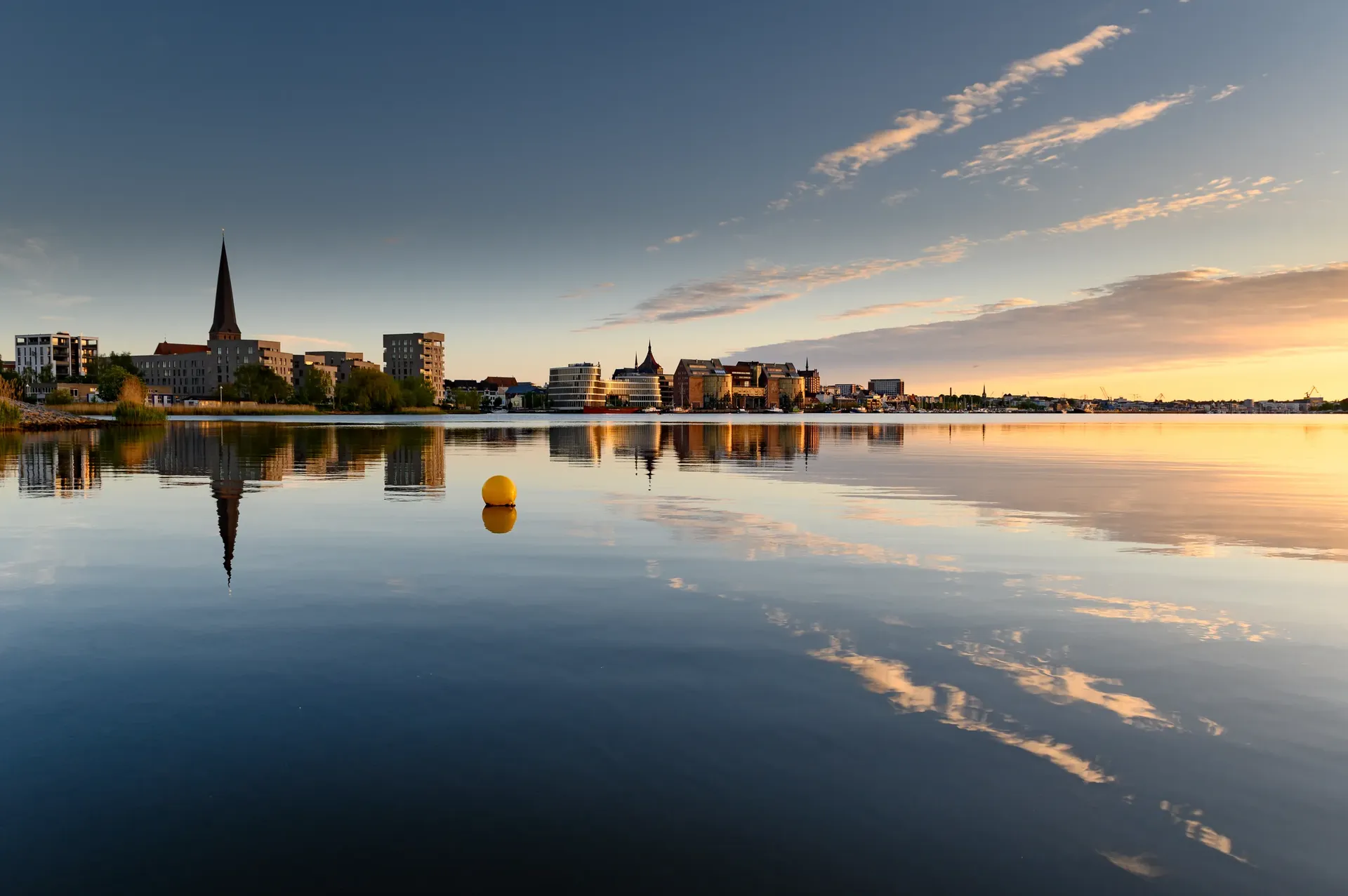 Die Rostocker Stadtsilhouette spiegelt sich im Wasser der Warnow