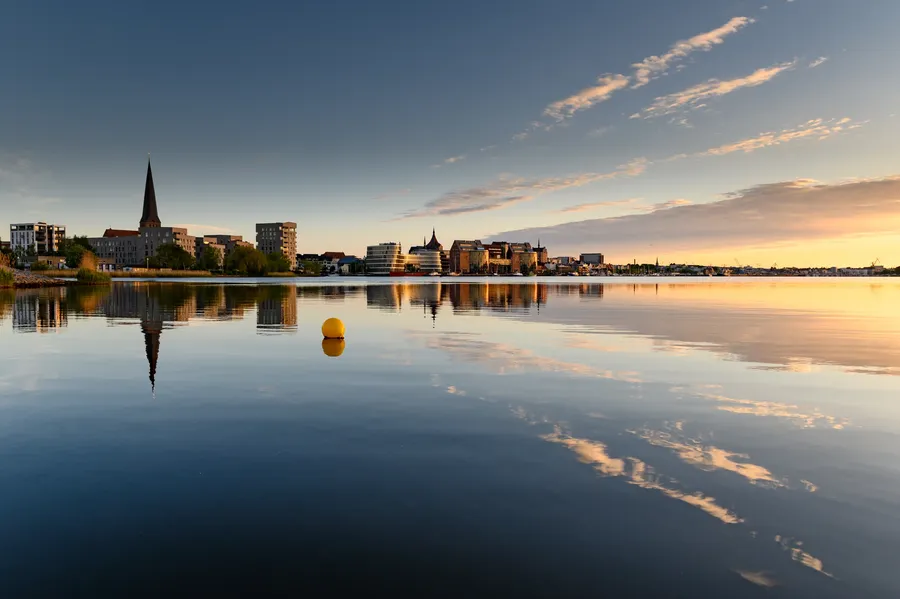 Die Rostocker Stadtsilhouette spiegelt sich im Wasser der Warnow