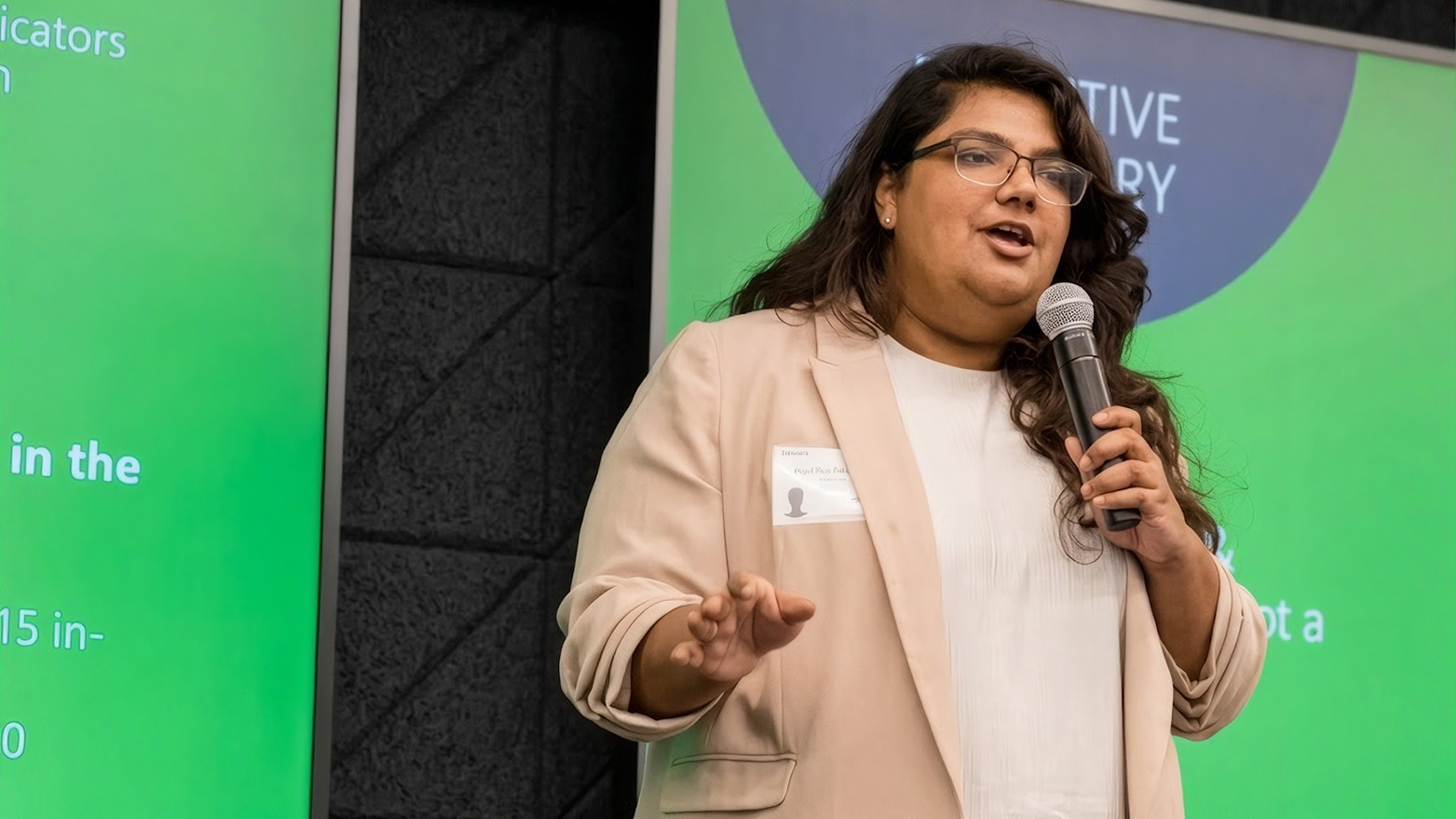 Priyanka speaking into a microphone on stage at a Hult event