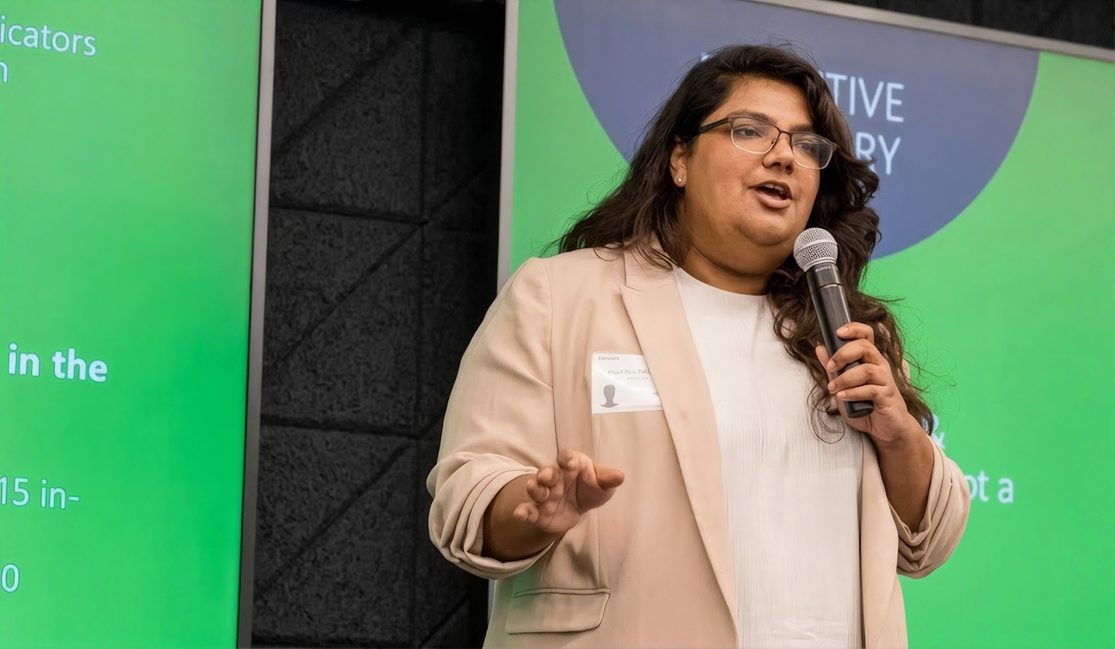 Priyanka speaking into a microphone on stage at a Hult event