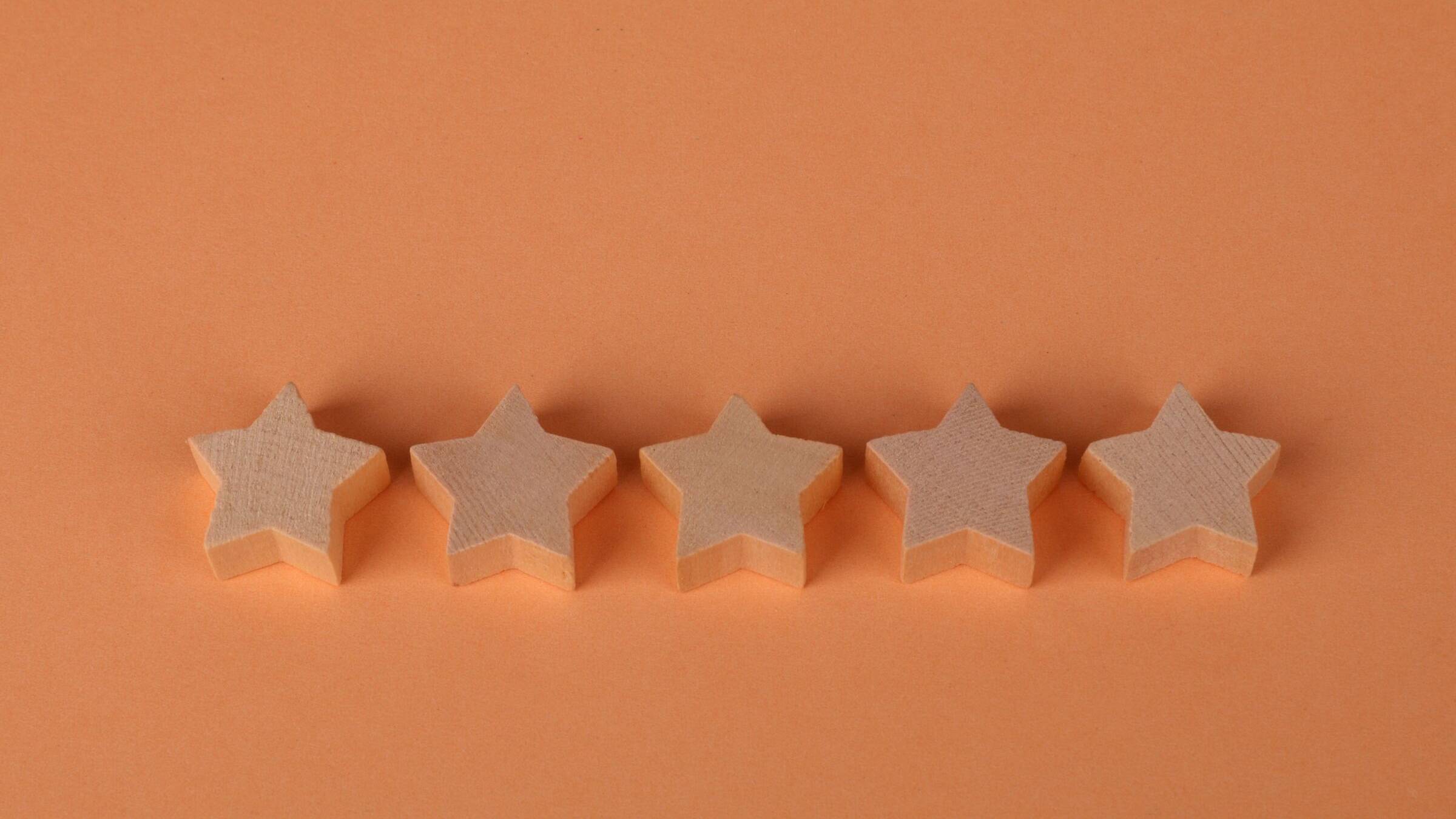 Five wooden stars in a row on an orange background