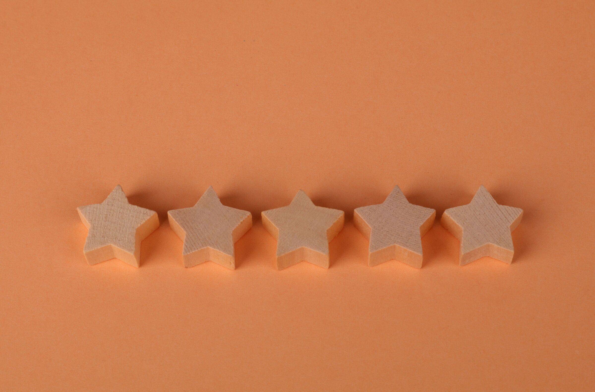 Five wooden stars in a row on an orange background
