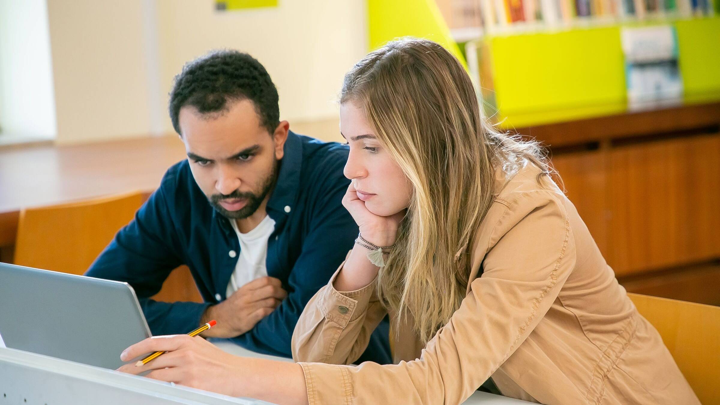 Two students leaning over a laptop together, weighing up their options