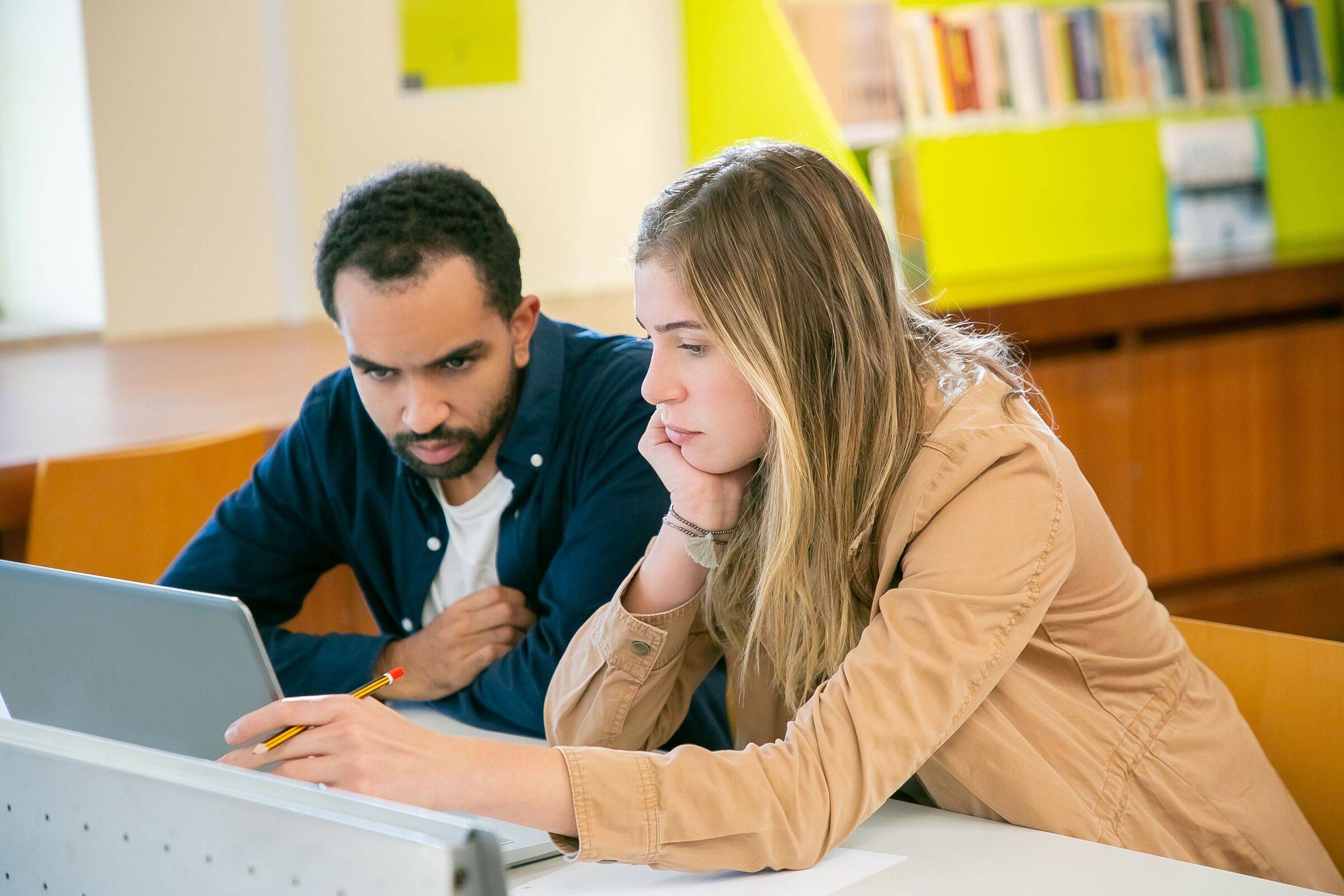 Two students leaning over a laptop together, weighing up their options