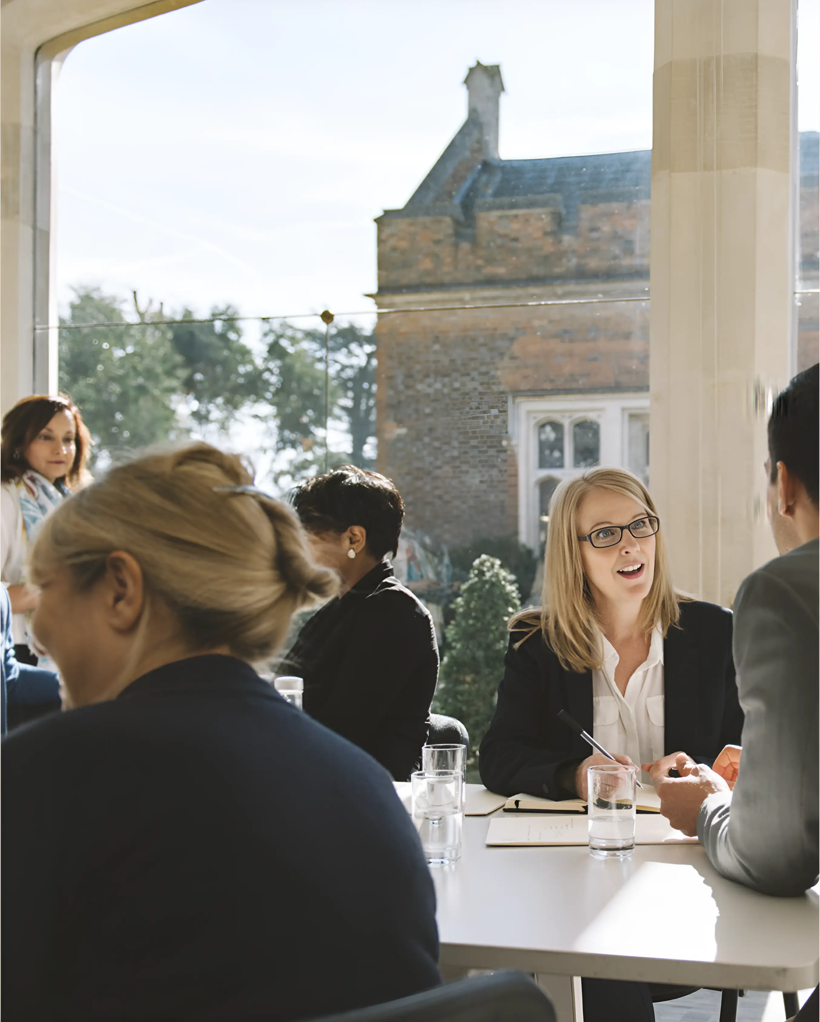 People engaged in a business meeting at a windowed conference room with a scenic view.
