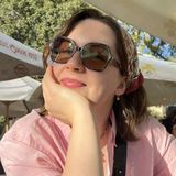 Portret Kingi Cios, psycholożki SlowSoul.me – uśmiechnięta, w okularach przeciwsłonecznych i chuście na włosach, opiera głowę na dłoni
