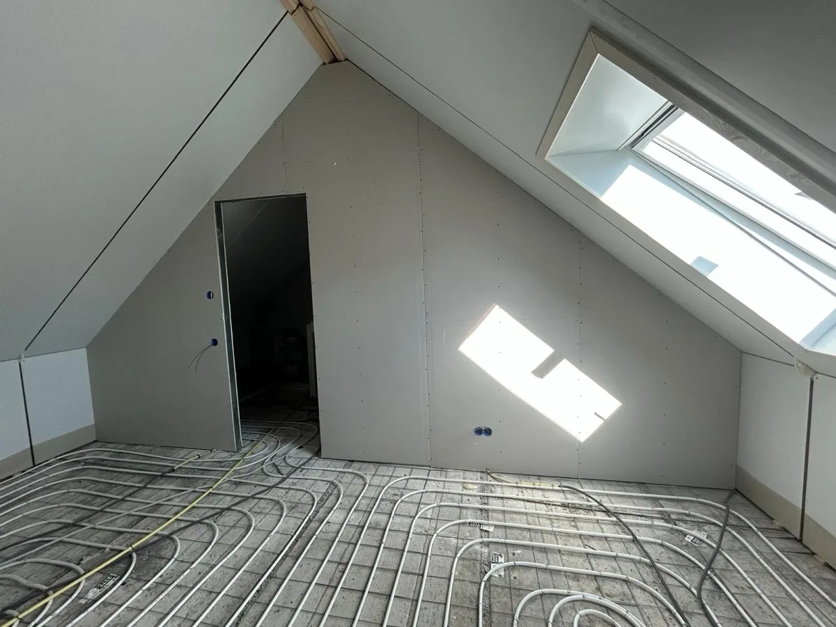 De zolder met de leidingen van de vloerverwarming in de vloer en de geplaatste wandbeplating.