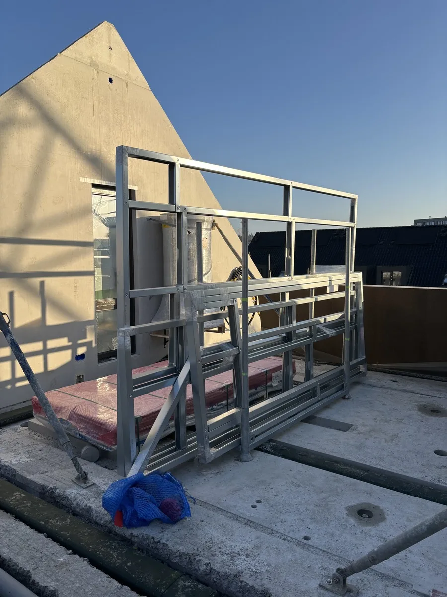 Een ingepakt Modulon-frame staat op de verdiepingsvloer, tegen de betonnen kopgevel van de woning.