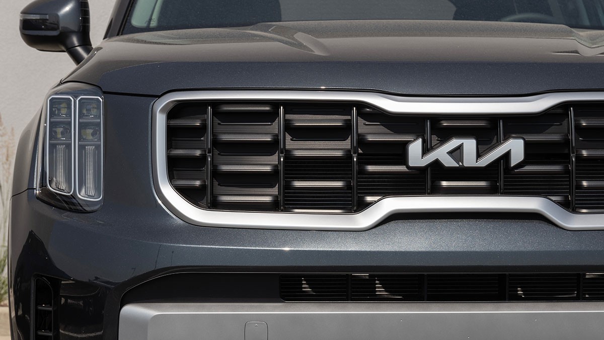 Front view of a dark gray Kia SUV showing its distinctive grille, modern headlights, and sleek emblem design.