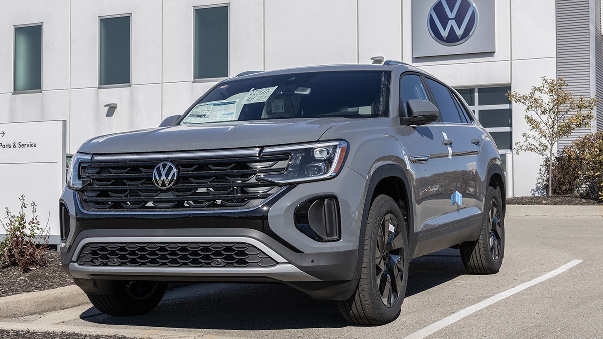 Gray Volkswagen SUV parked in front of a dealership building, with visible signage and a paper on the windshield.